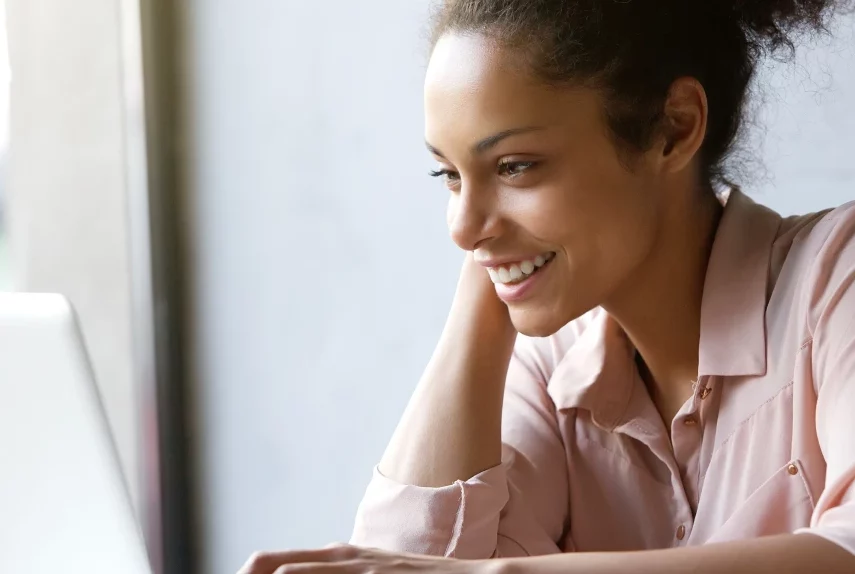 Woman smiling at her laptop – online psychiatry in Livonia, MI